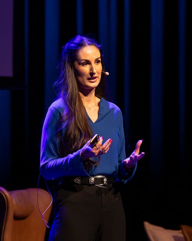 Hana Colakovic på scenen i blå bluse, midt i et foredrag