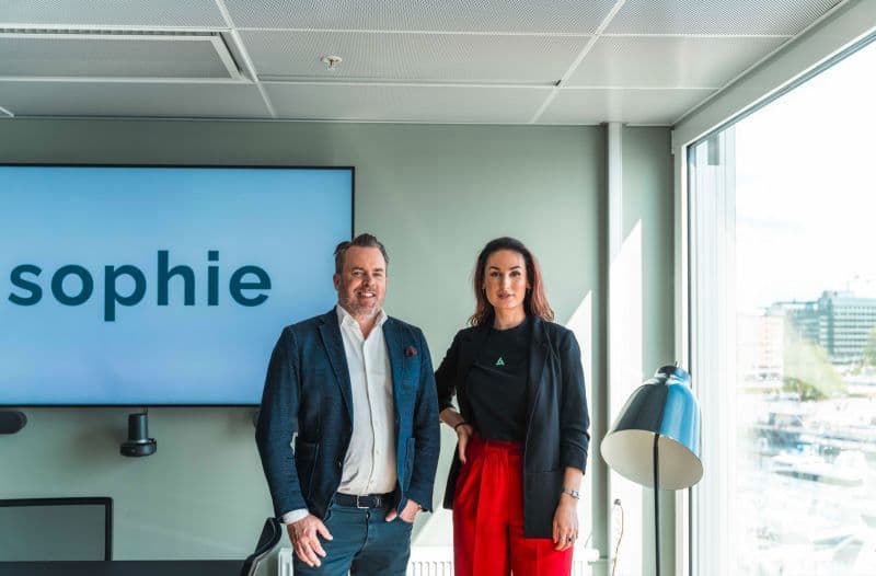 Hana Colakovic sammen med Sophie-gründer foran selskapets logo